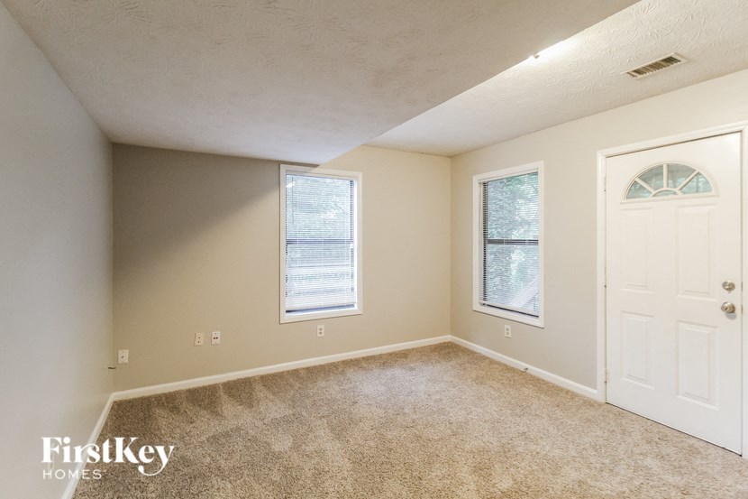 an empty room with a white door and two windows