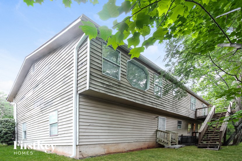 a white house with gray siding and green grass and trees