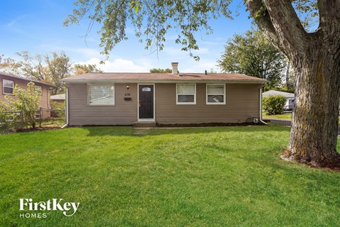 a small brown house with a yard and a tree