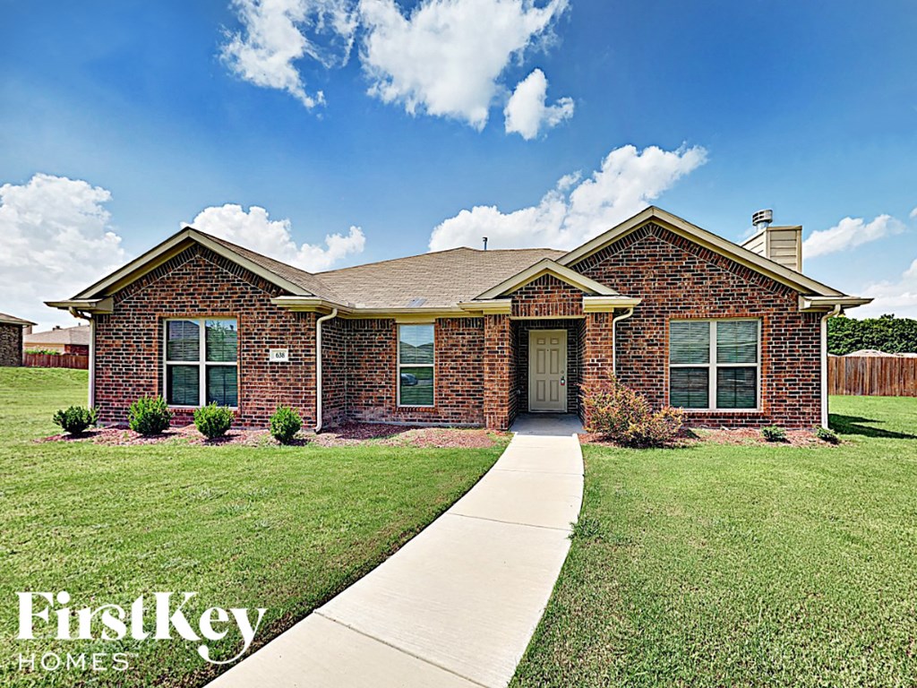 A brick house with a white door and windows is for sale.