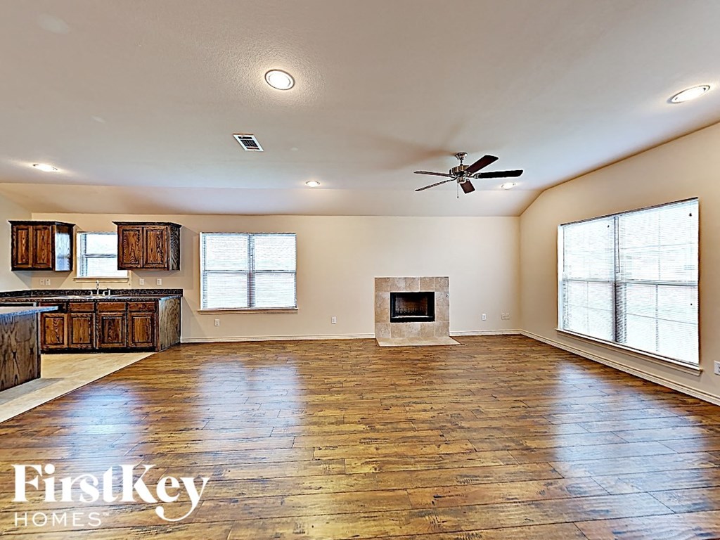 A spacious room with wooden floors and a fireplace.