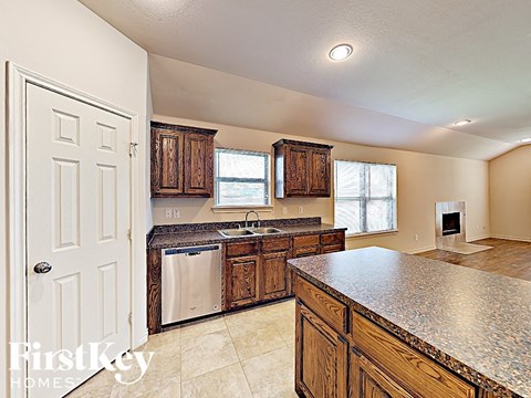 A kitchen with a granite counter top and wooden cabinets.