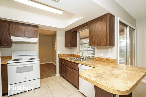 A kitchen with a white stove and wooden cabinets.