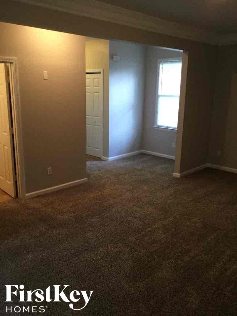 A room with a carpeted floor and a window with light coming through.