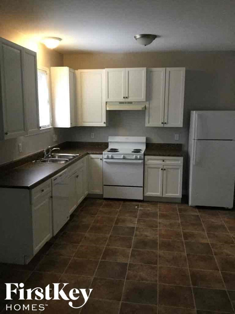 A kitchen with white cabinets and a tiled floor.