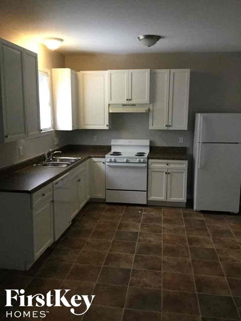 A kitchen with white cabinets and a tiled floor.