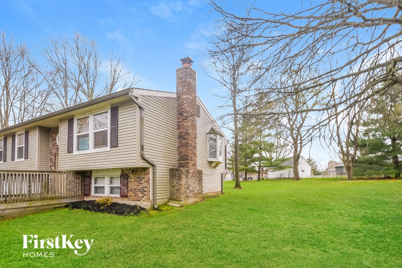 a house with a brick chimney on the side of a green lawn
