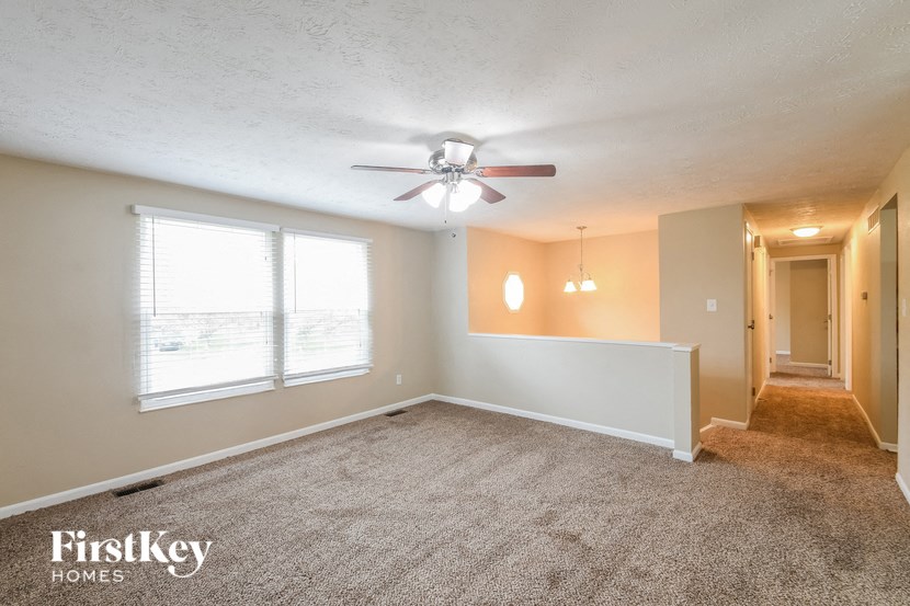an empty living room with a ceiling fan and a large window
