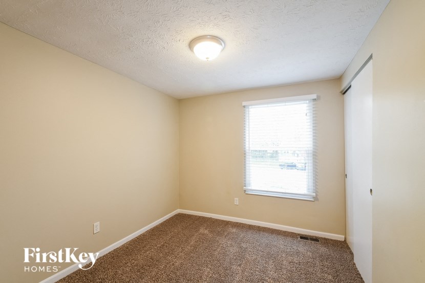 the living room of an empty home with a window and carpet