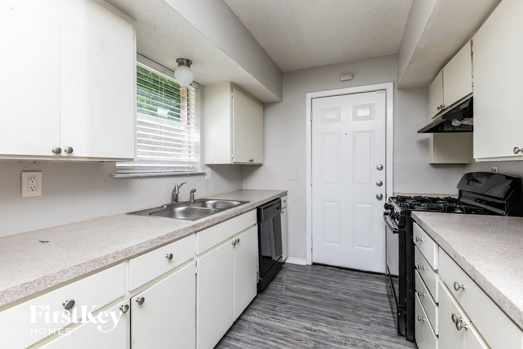 an empty kitchen with white cabinets and a sink