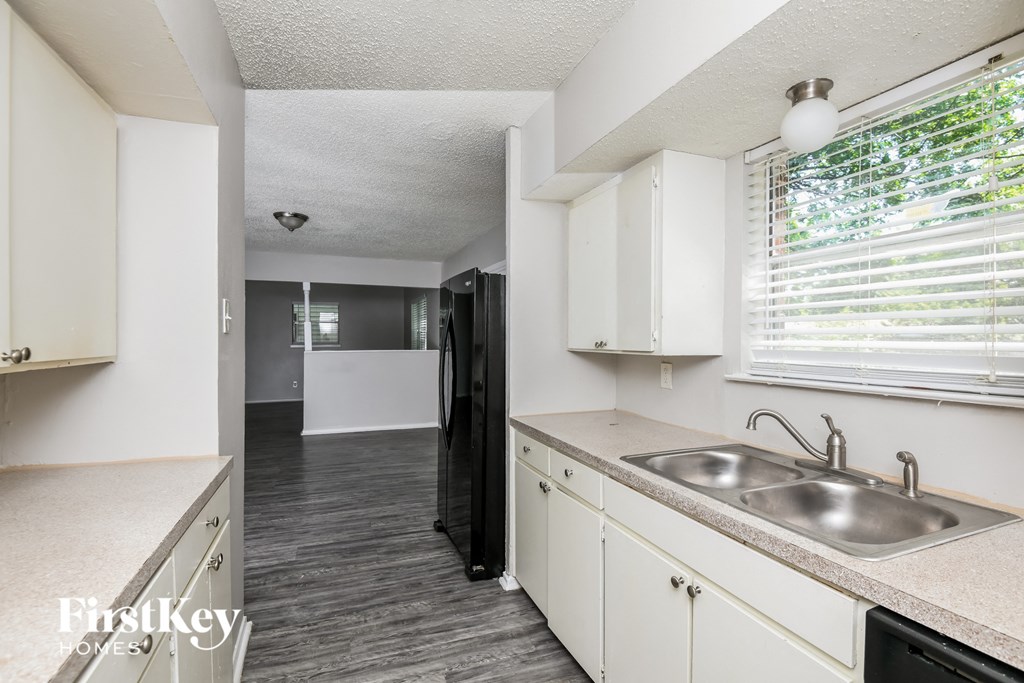 a kitchen and living room with white cabinets and a sink