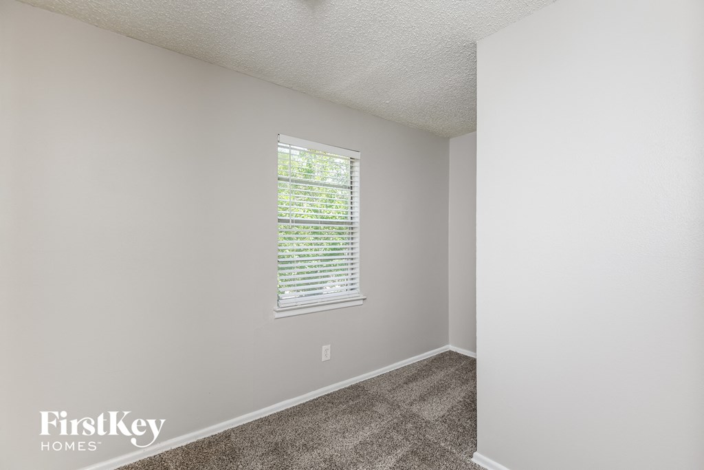 a bedroom with white walls and a window