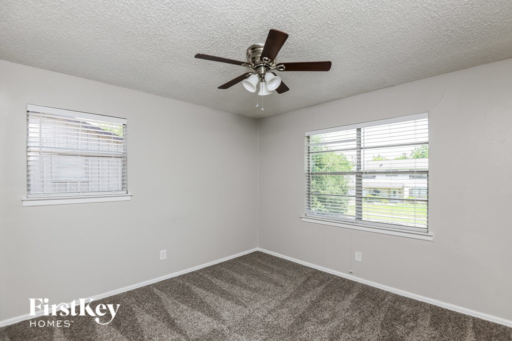 a bedroom with a ceiling fan and two windows