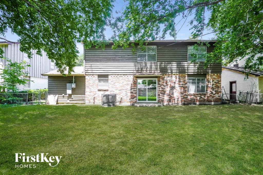 a house with a lawn and trees in front of it