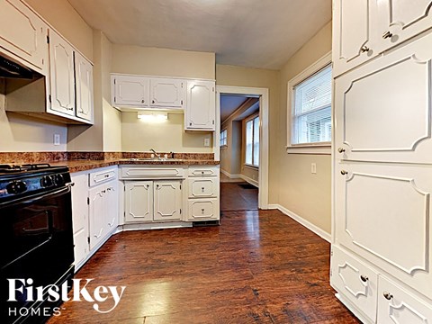 A kitchen with white cabinets and a black stove top oven.