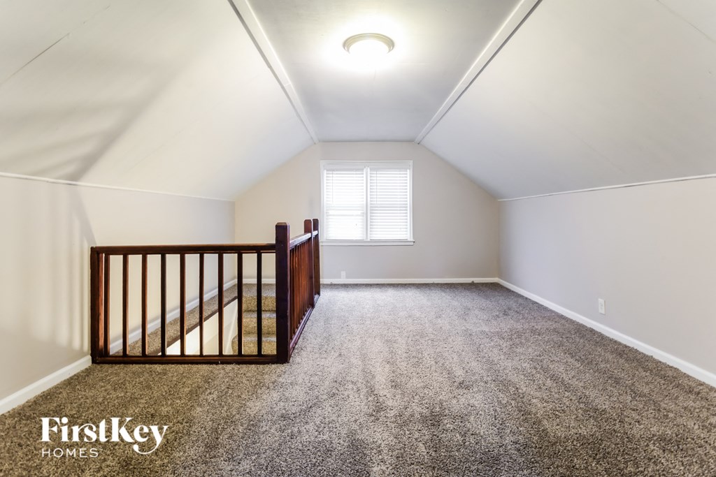 a loft with a crib and a carpeted floor and a window