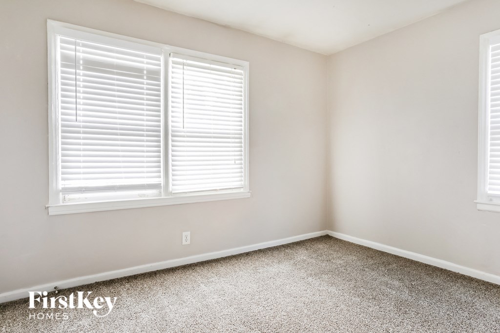 a bedroom with two windows and a carpeted floor