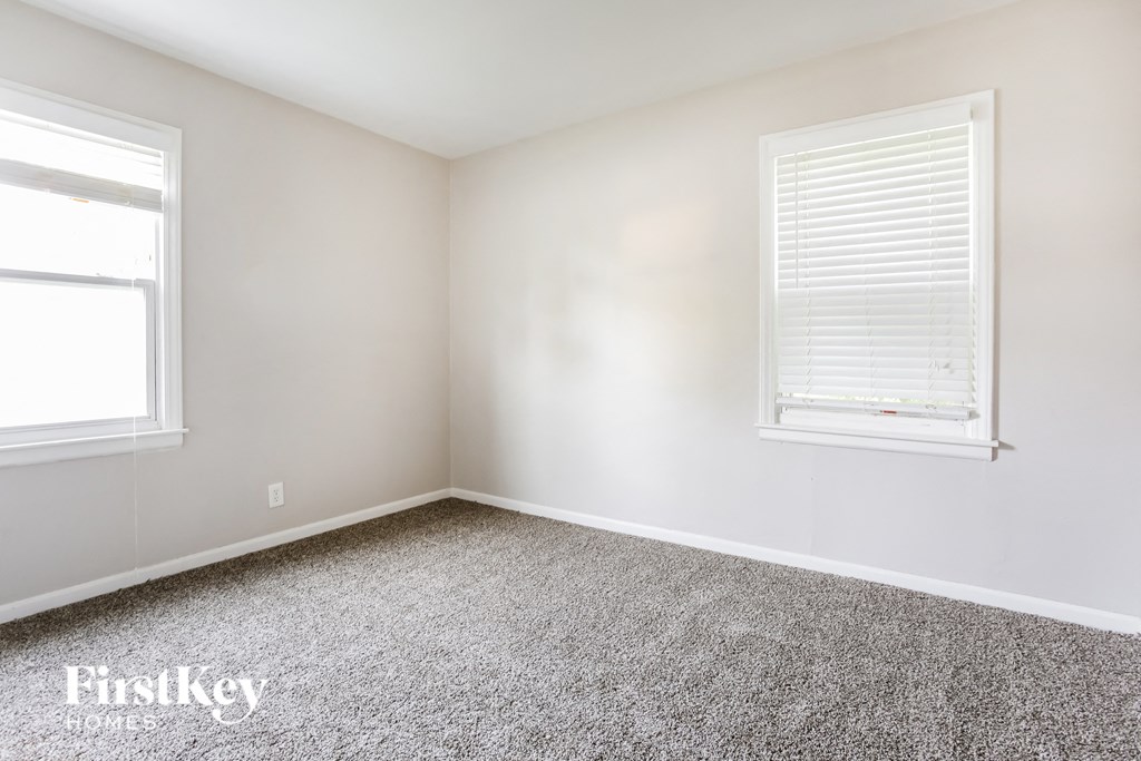 a bedroom with a carpeted floor and two windows