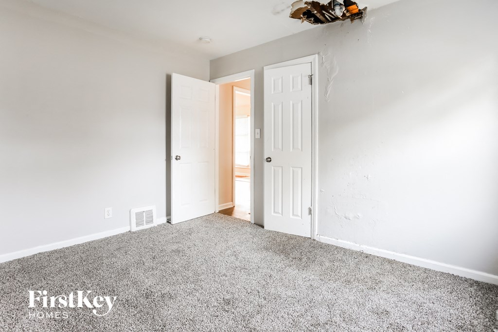 a bedroom with white walls and a white door and carpet