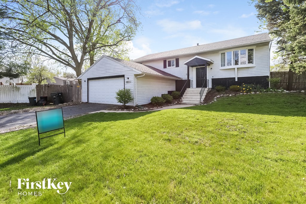 A white house with a black fence and a blue sign in front of it.