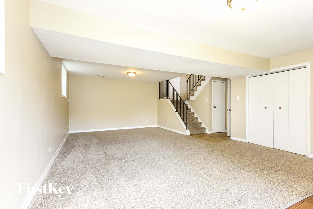 A spacious room with a staircase and a white door.