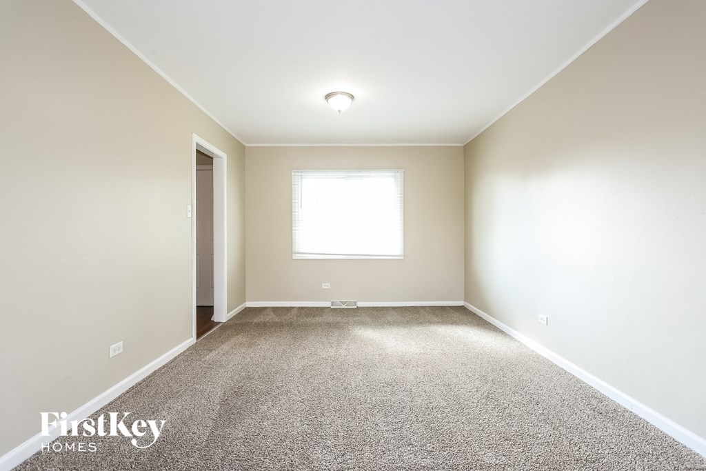 A carpeted room with a window and a door.