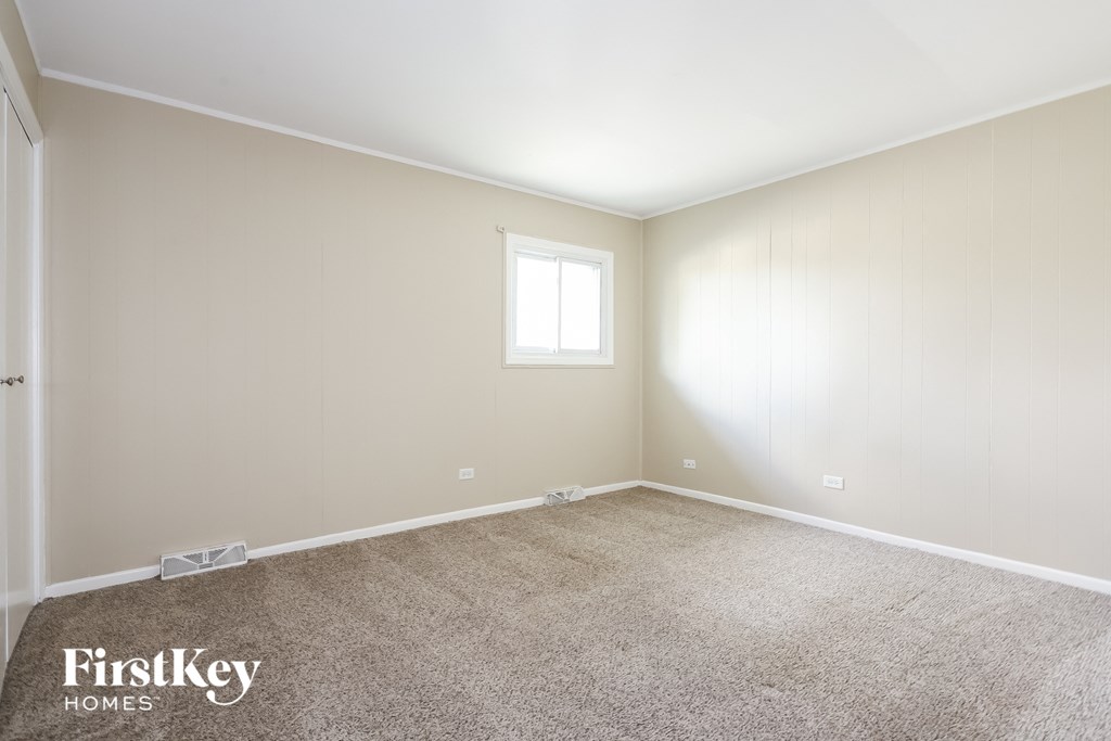 A room with a carpeted floor and a window letting in sunlight.