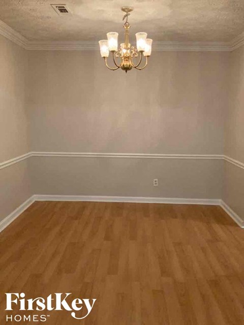 A room with wooden flooring and a chandelier.