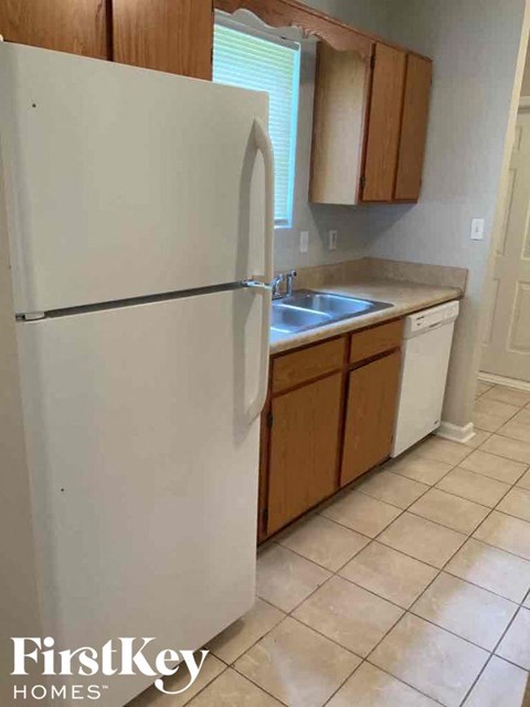 A white refrigerator in a kitchen with wooden cabinets.