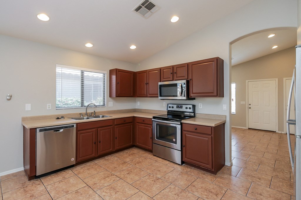 A kitchen with brown cabinets and a tiled floor.