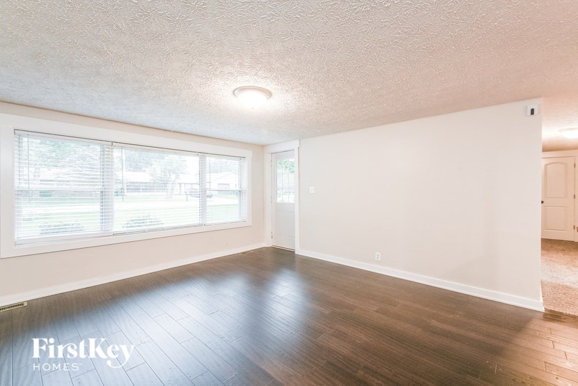 A room with wooden floors and a large window with blinds.