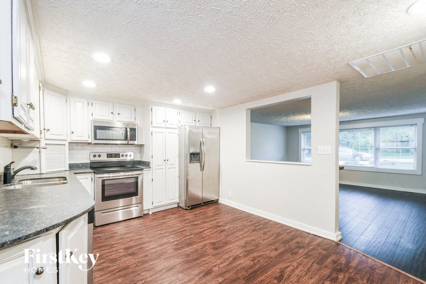 A kitchen with white cabinets and a stainless steel refrigerator.