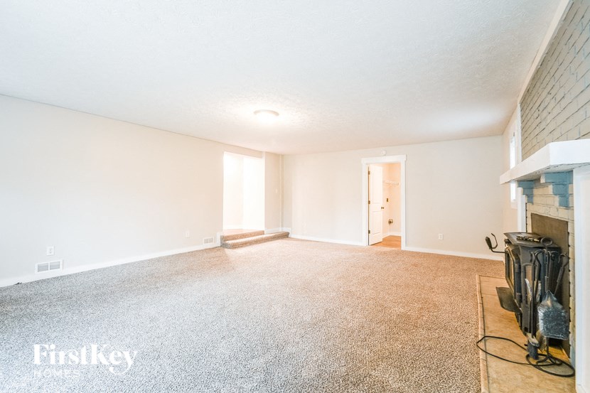 A room with a carpeted floor and a fireplace.