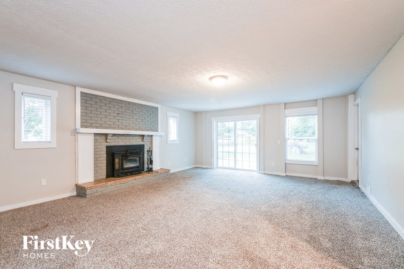 A spacious room with a fireplace and carpeted floor.