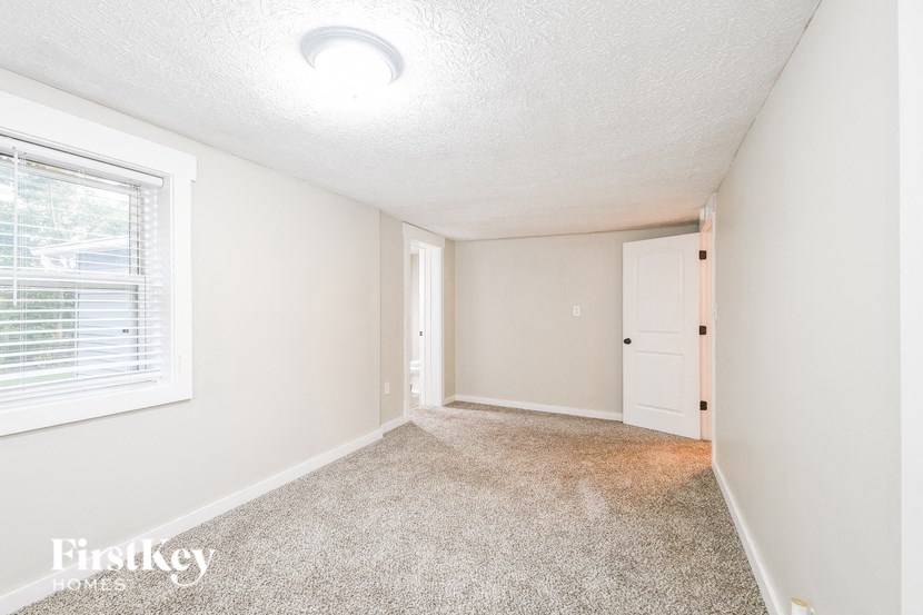 A room with a carpet floor and a window with blinds.