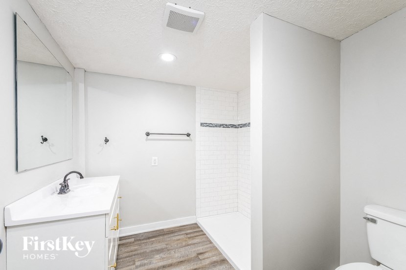 A white bathroom with a sink, mirror, and toilet.