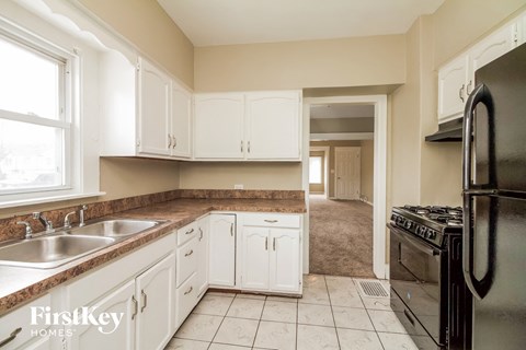 A kitchen with white cabinets and a black refrigerator.