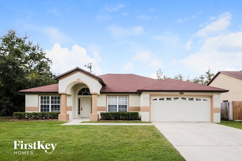 a beige house with a driveway and a lawn