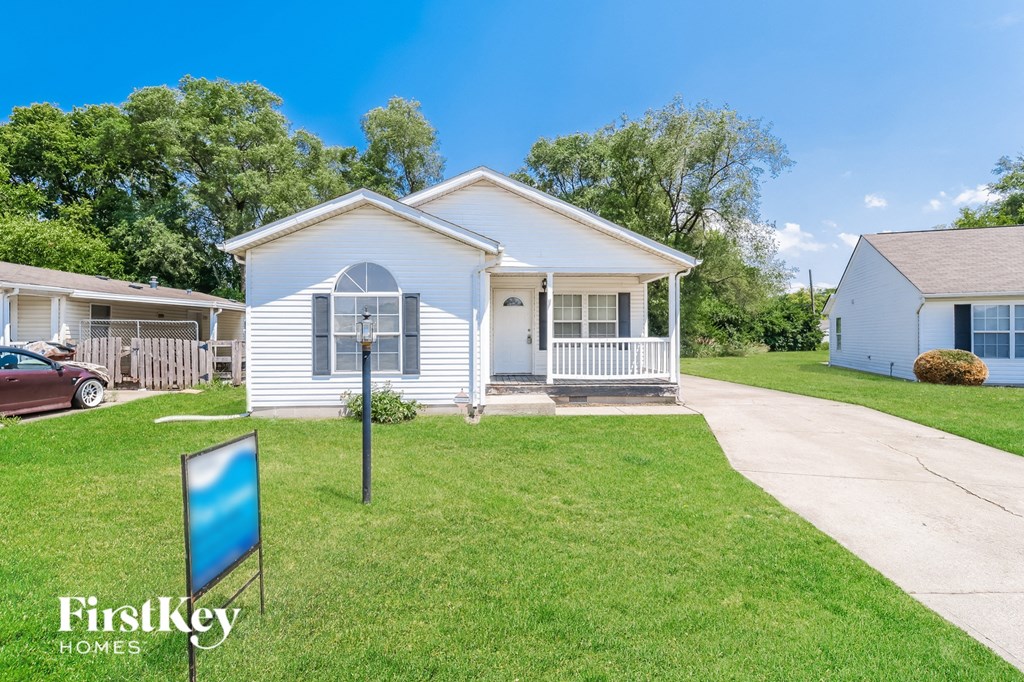 a white house with a yard and a blue sign in front of it