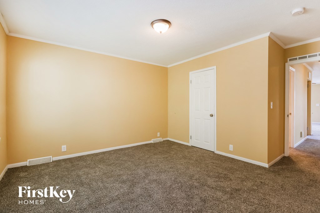 a carpeted living room with a white door and yellow walls