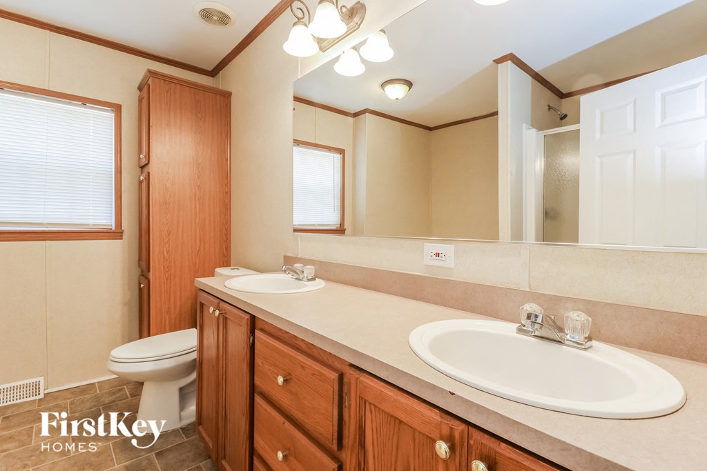 a bathroom with two sinks and a toilet and a mirror