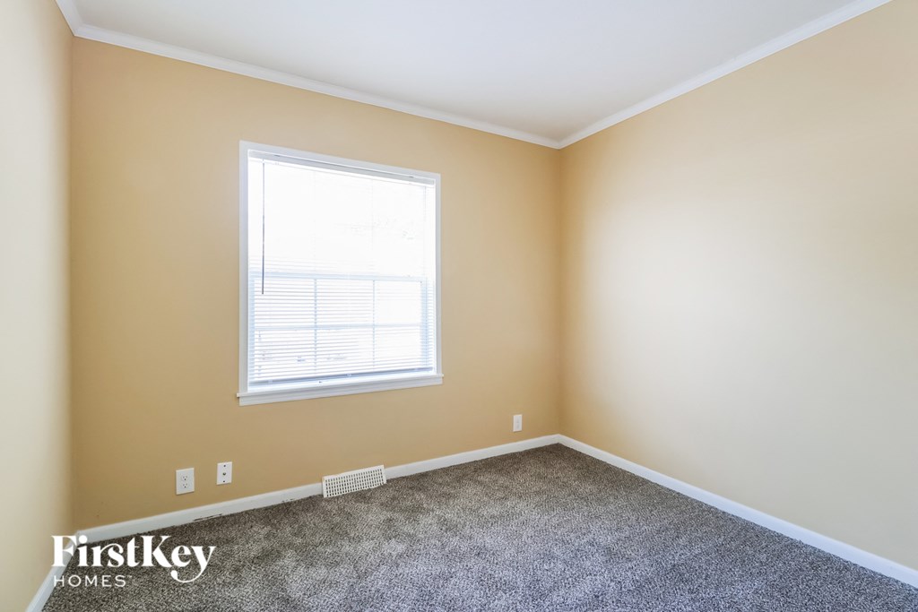 a bedroom with a window and a carpeted floor