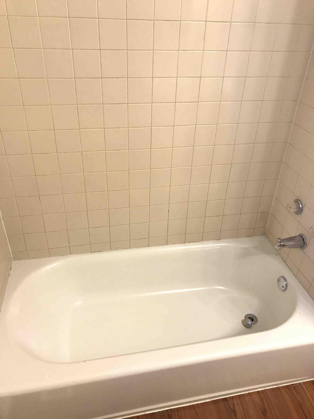 a white bath tub in a white tiled bathroom
