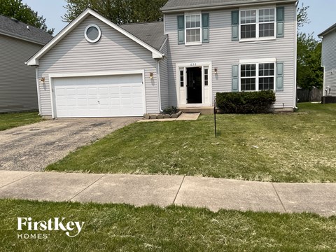 A house with a garage and a driveway in front of it.