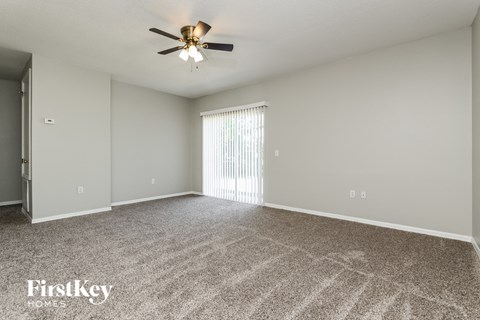 A spacious room with a ceiling fan and carpeted floor.