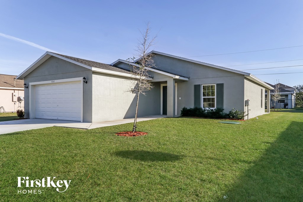 a white house with a lawn and a tree in the front