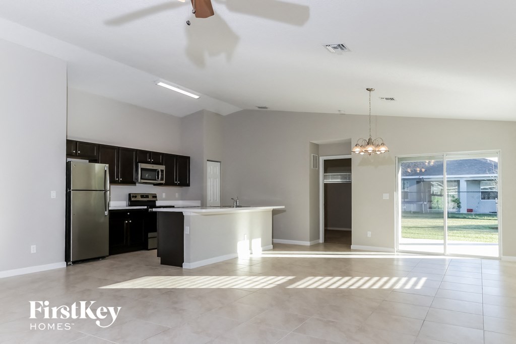 an empty kitchen with an island and a stainless steel refrigerator