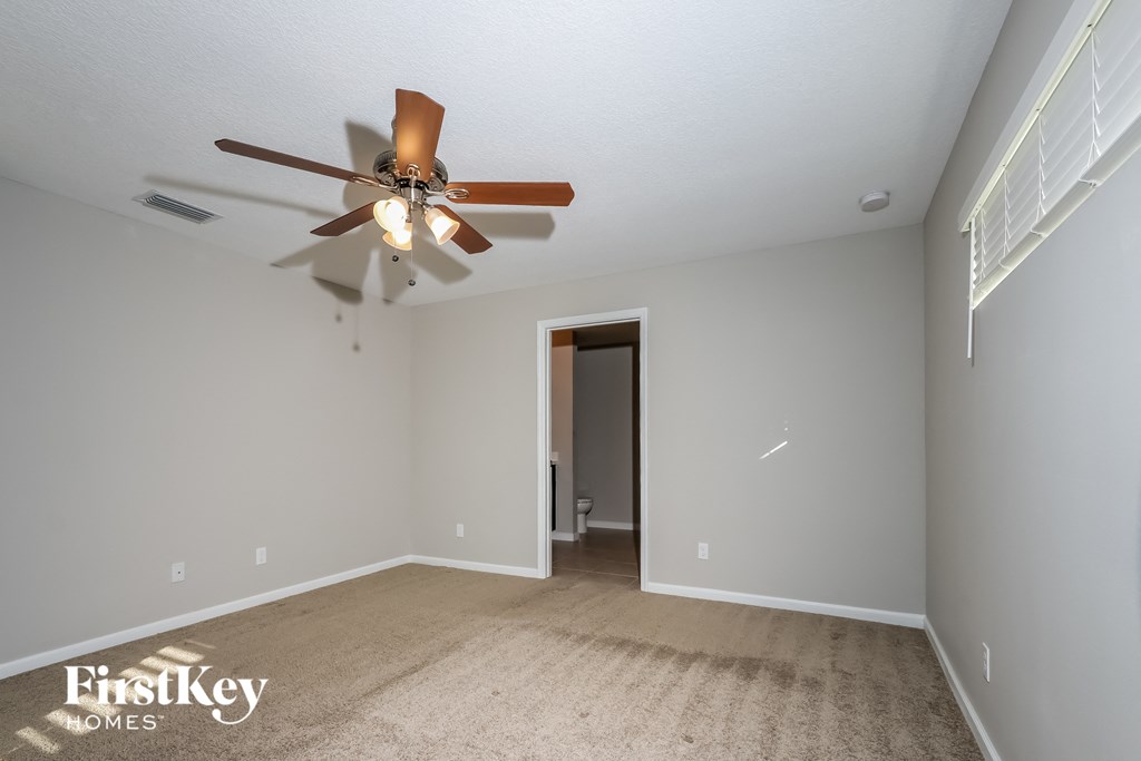 a living room with a ceiling fan and a carpet