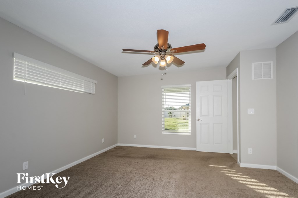 an empty living room with a ceiling fan and a window