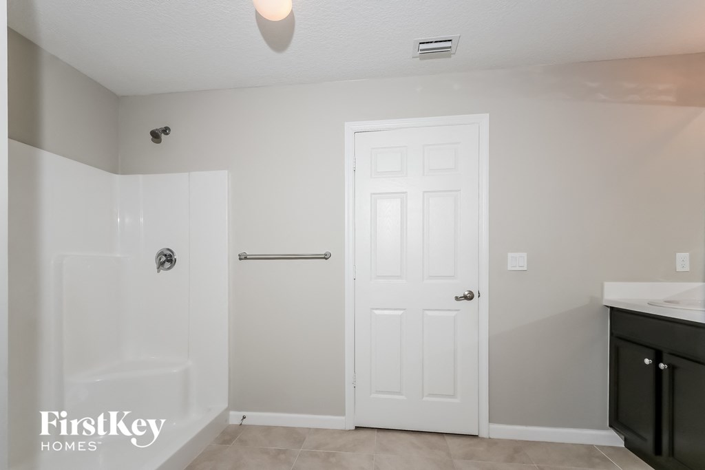 a bathroom with a white door and a shower and a sink